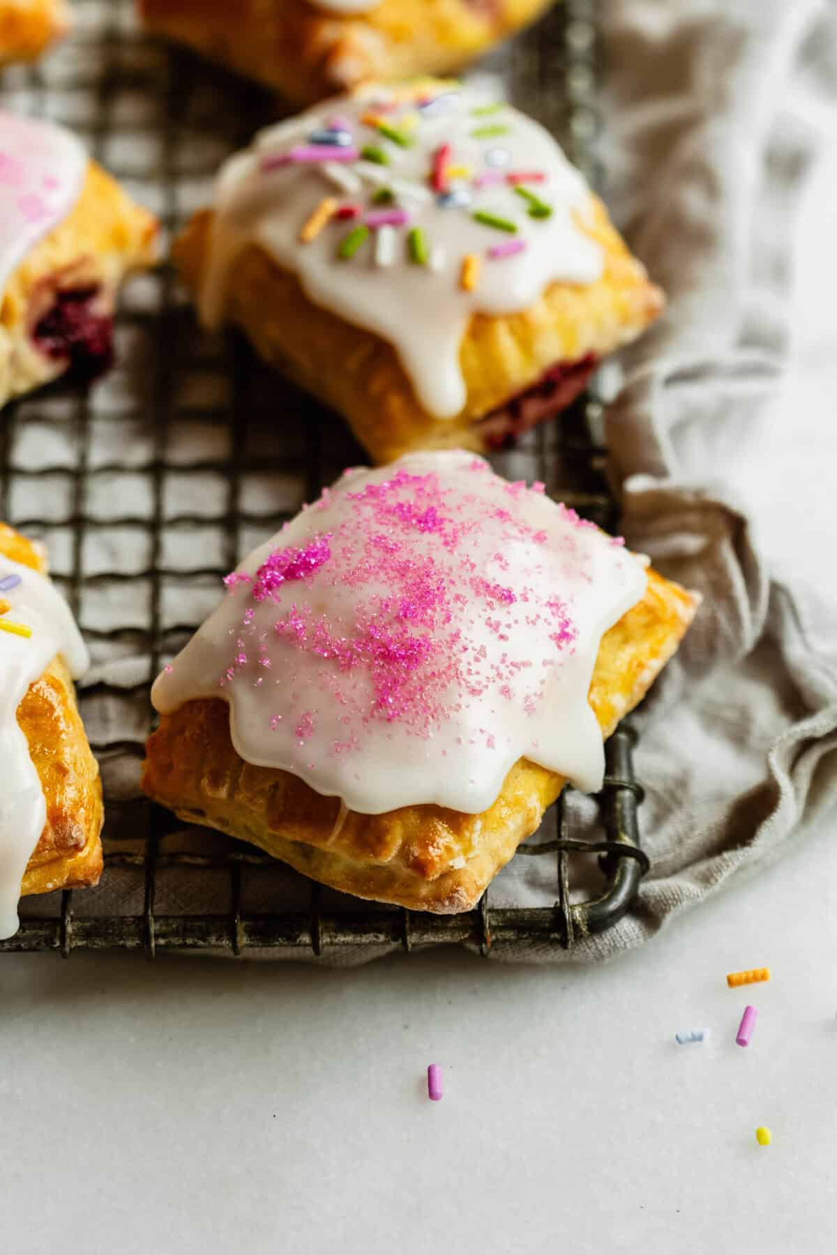 Cottage cheese dough pop tarts on a wire rack topped with sprinkles.