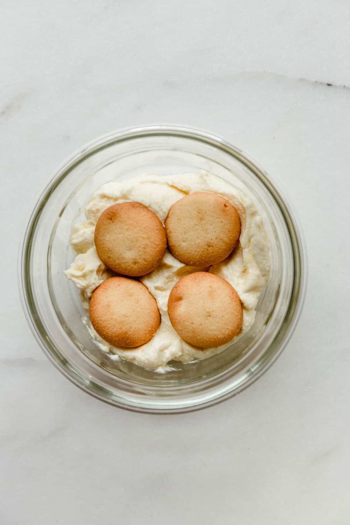 nilla wafers on greek yogurt pudding in a clear container.