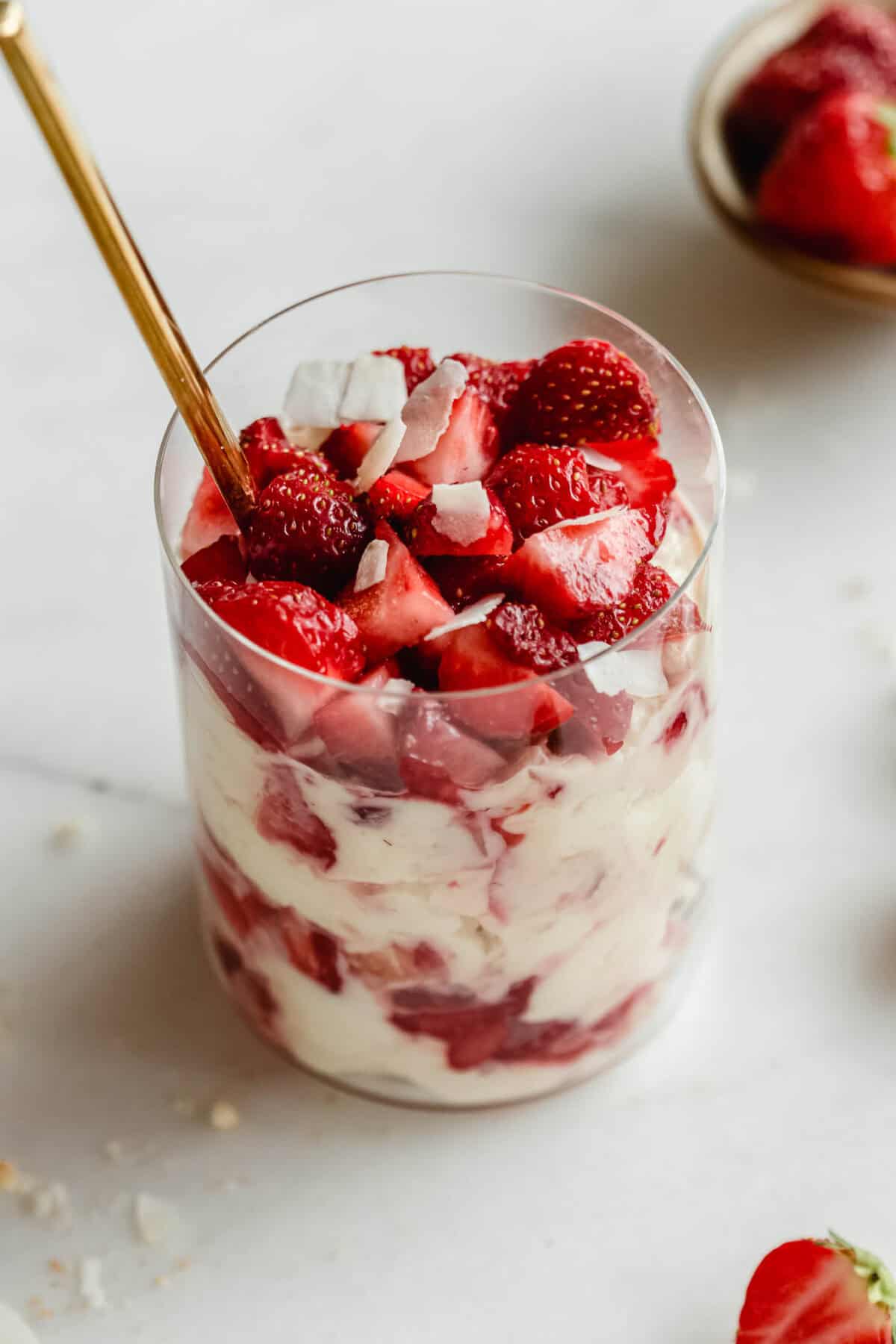 Strawberry pudding jars made with Greek yogurt, Nilla wafers, and vanilla pudding mix with a gold spoon in it.