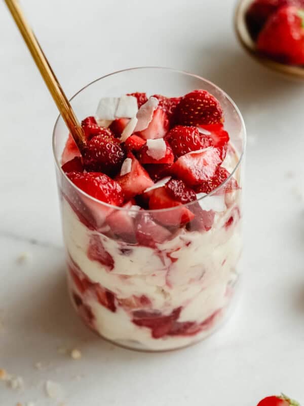 Strawberry pudding jars made with Greek yogurt, Nilla wafers, and vanilla pudding mix with a gold spoon in it.