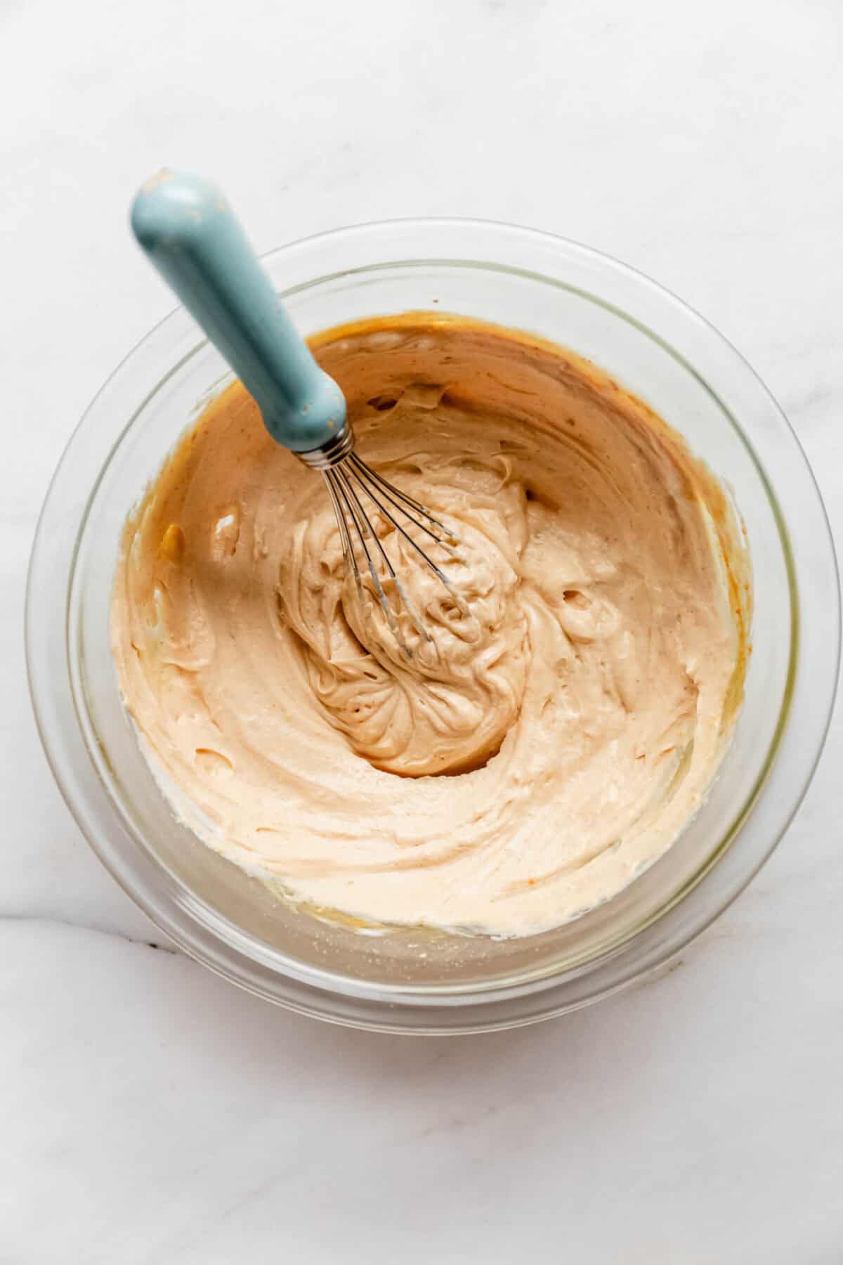 Whisking a creamy peanut butter mousse mixture in a glass bowl.