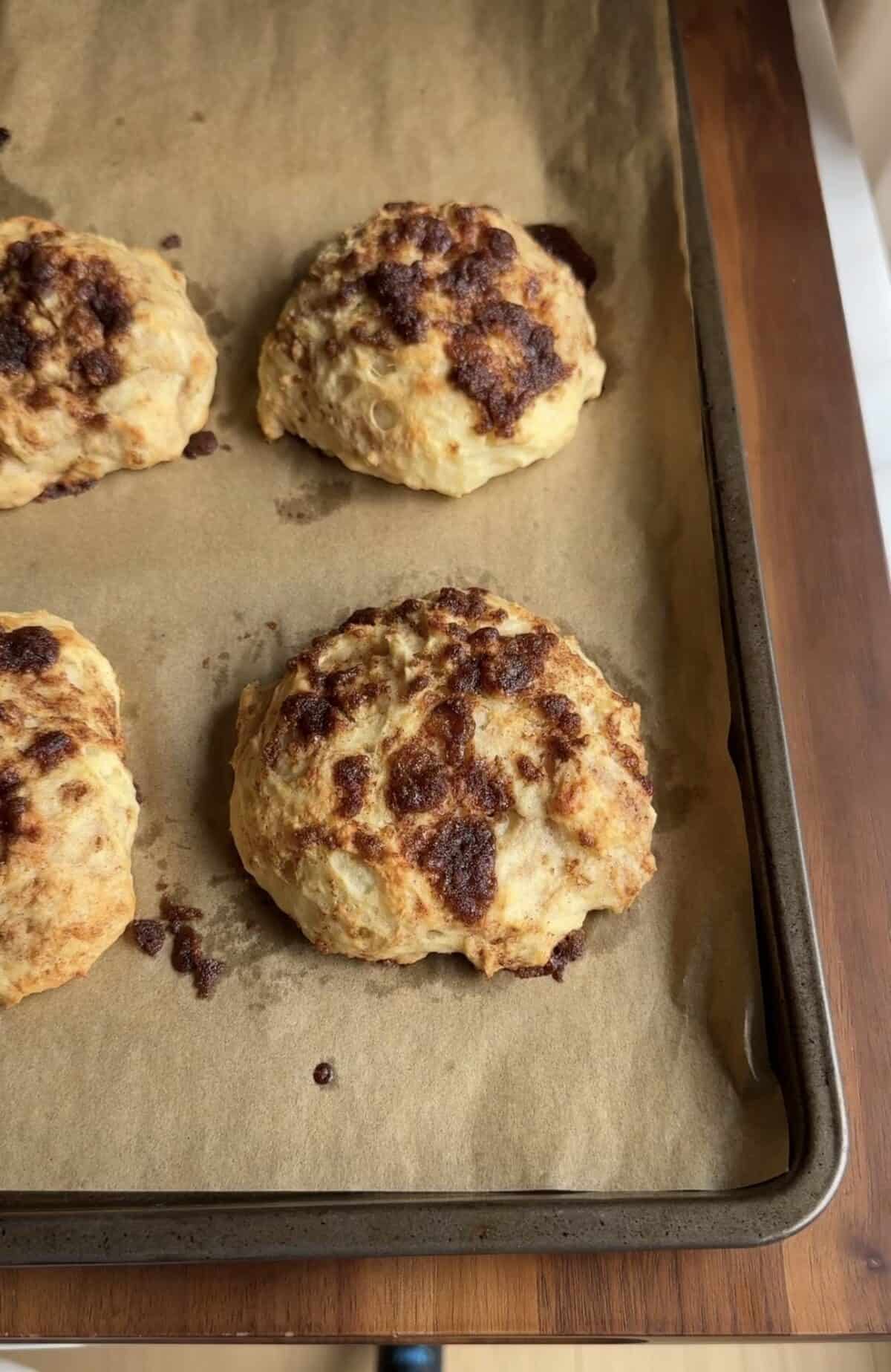 four cottage cheese cinnamon crunch biscuits on a baking sheet.