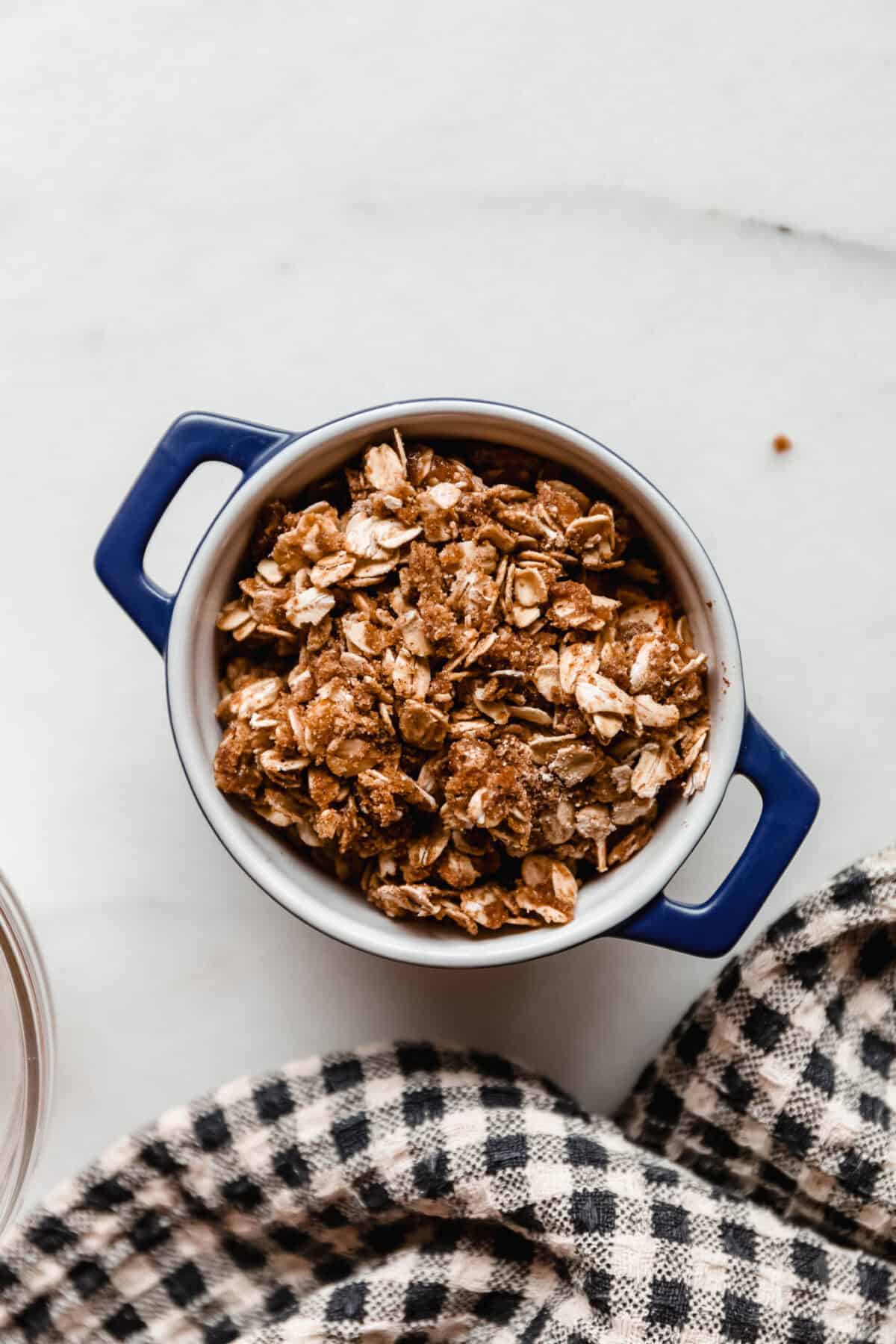 An unbaked apple crisp topped with crumble mixture in a blue baking dish, ready for the air fryer.