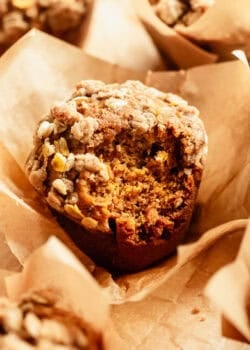 Close-up of a banana pumpkin muffin with an oat crumble topping in a paper liner.