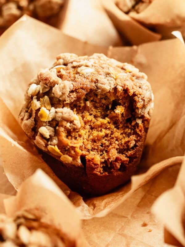 Close-up of a banana pumpkin muffin with an oat crumble topping in a paper liner.