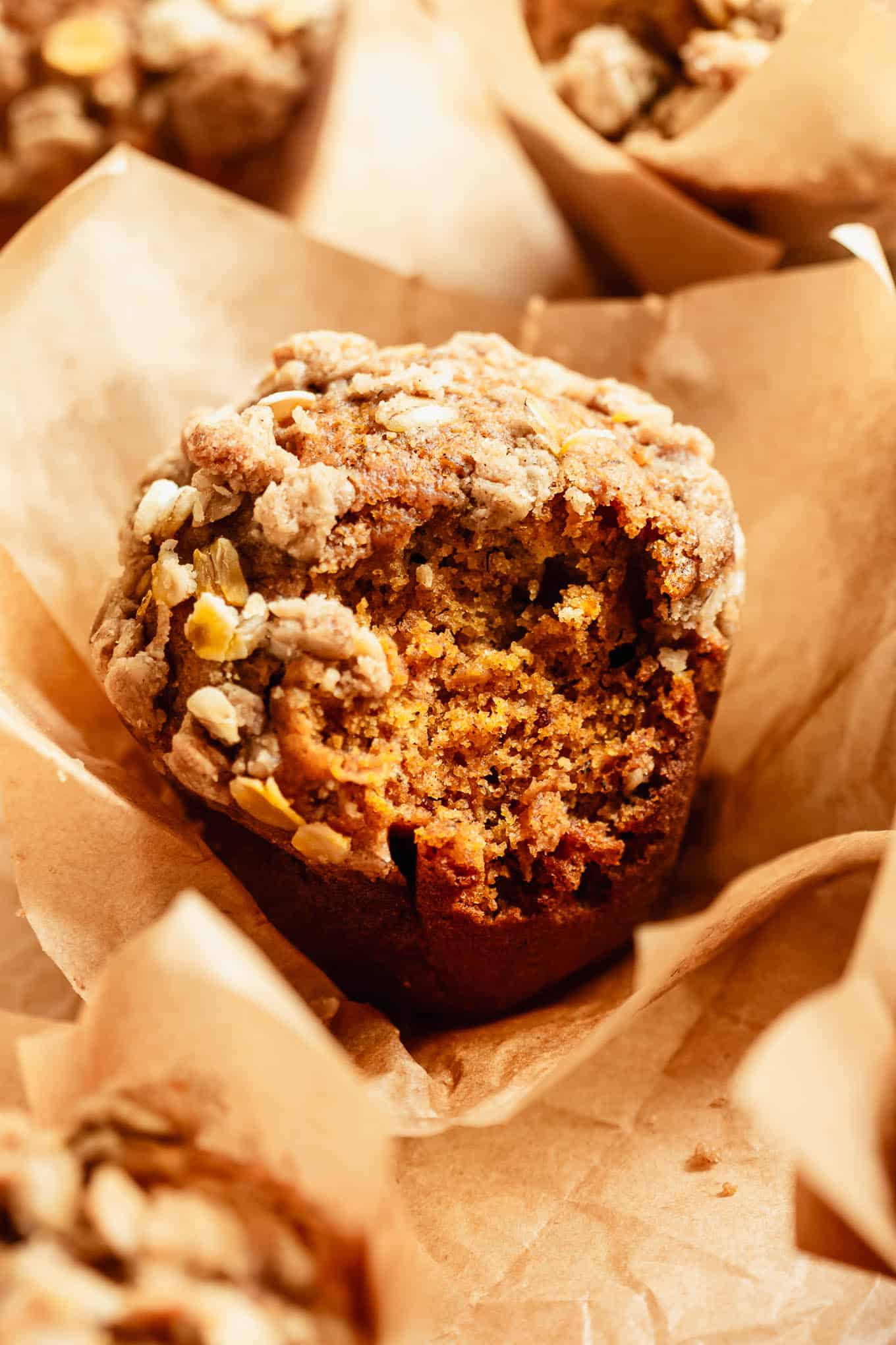 Close-up of a banana pumpkin muffin with an oat crumble topping in a paper liner.
