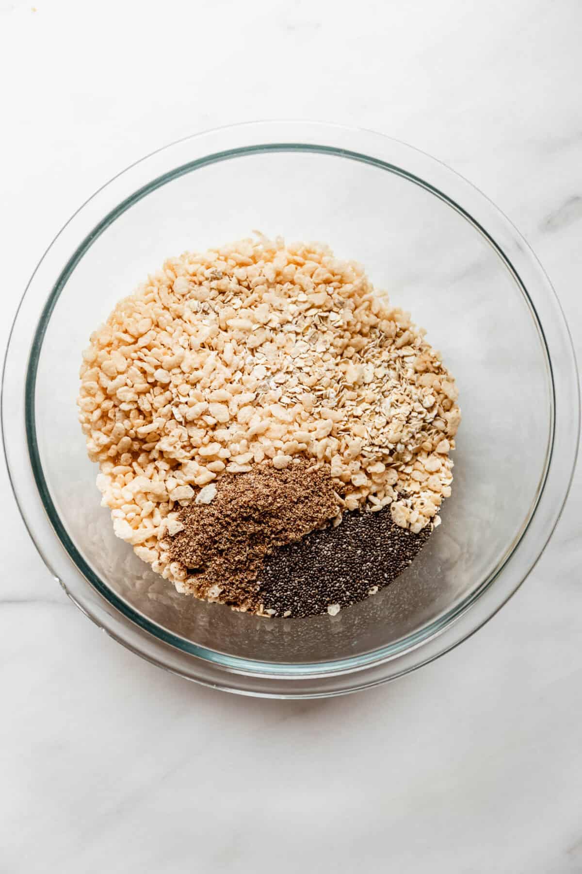 Bowl of oats, crispy rice cereal, cocoa powder, and chia seeds for copycat chewy s'mores granola bars.