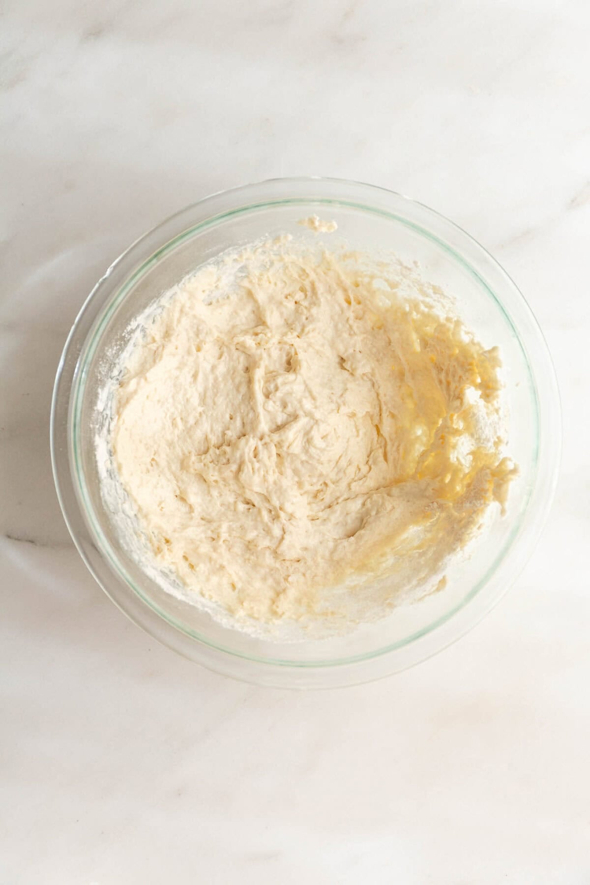 Overhead view of shaggy cottage cheese biscuit dough being mixed in a glass bowl