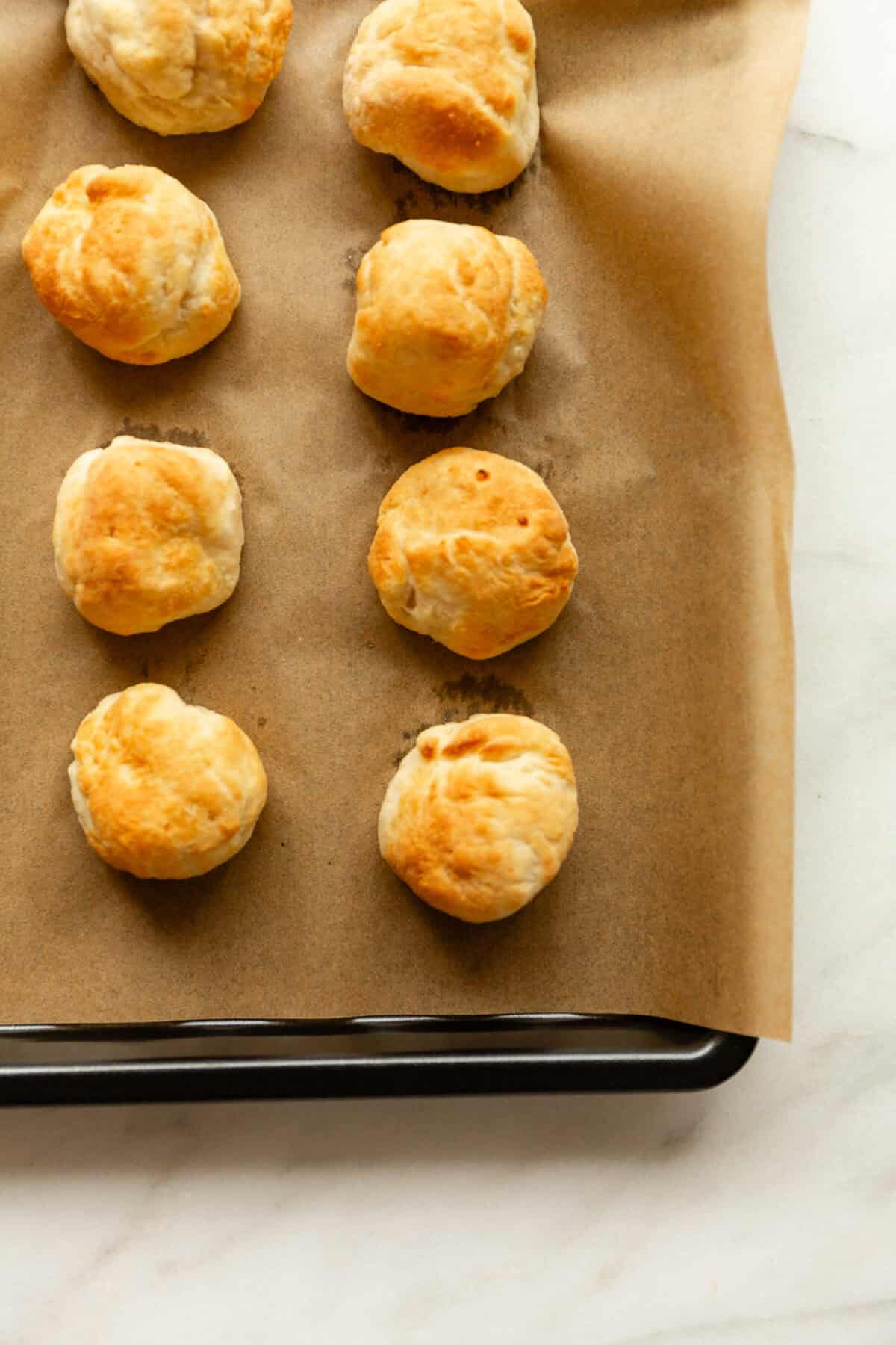 Rows of freshly baked golden brown donut holes on a parchment-lined baking sheet.