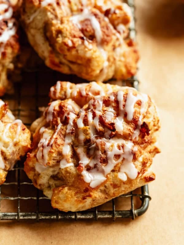Close-up of glazed cottage cheese apple fritters stacked on a cooling rack.