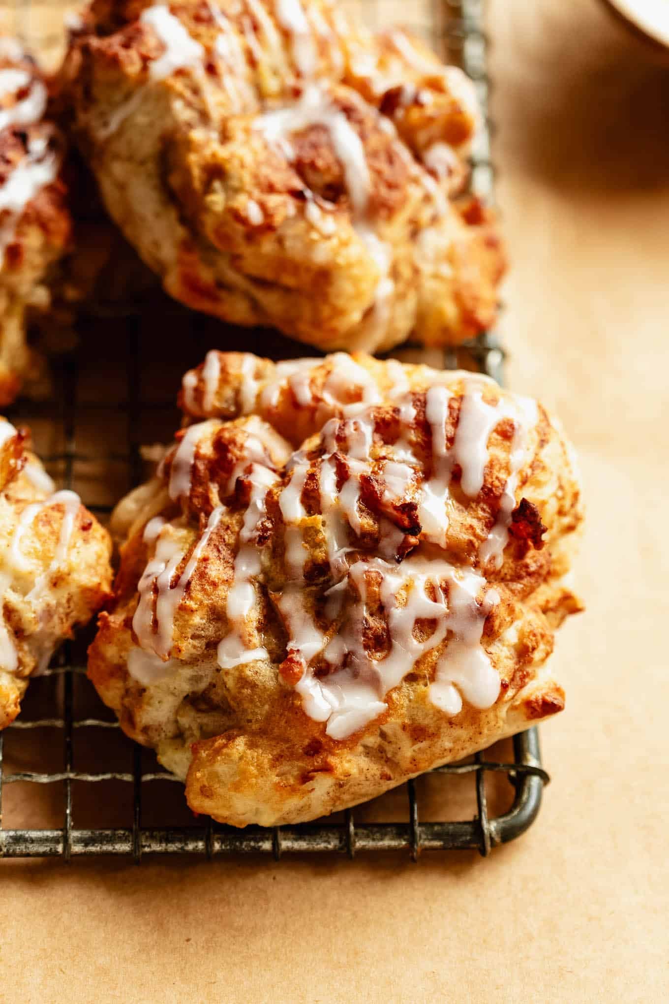Close-up of glazed cottage cheese apple fritters stacked on a cooling rack.