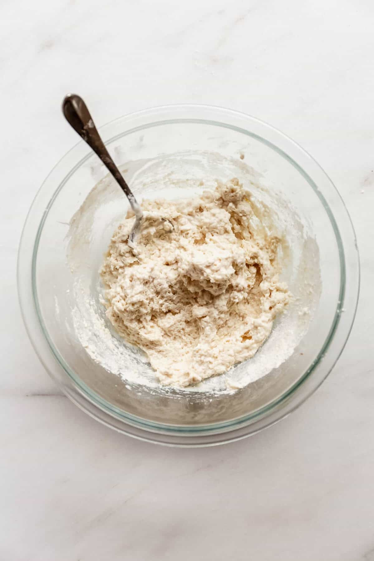 Bowl of dry flour mixture for cottage cheese apple fritters with a spoon.