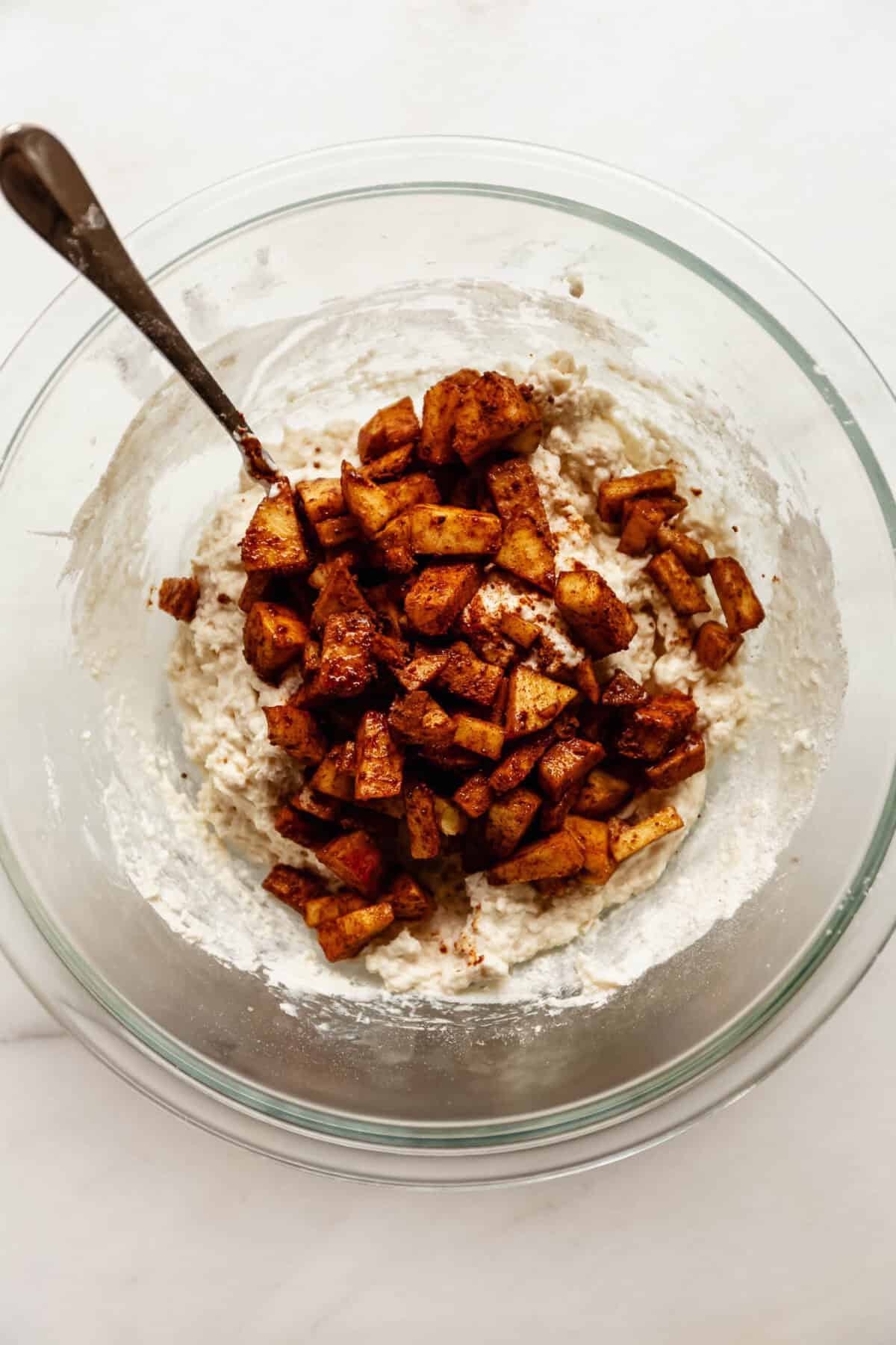 Bowl of cottage cheese fritter batter mixed with diced cinnamon apples.