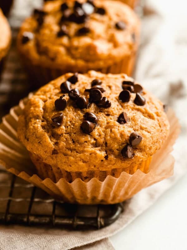 Close-up of a cottage cheese pumpkin chocolate chip muffin in a paper liner on a wire cooling rack.