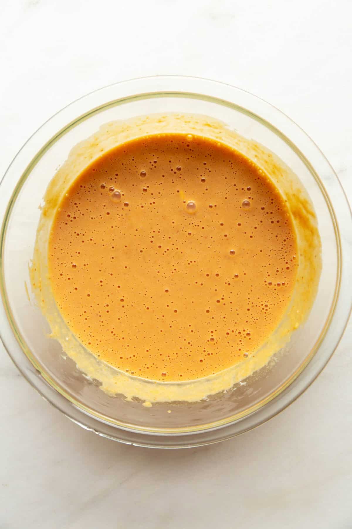 Cottage cheese pumpkin muffin batter blended smooth in a glass mixing bowl.