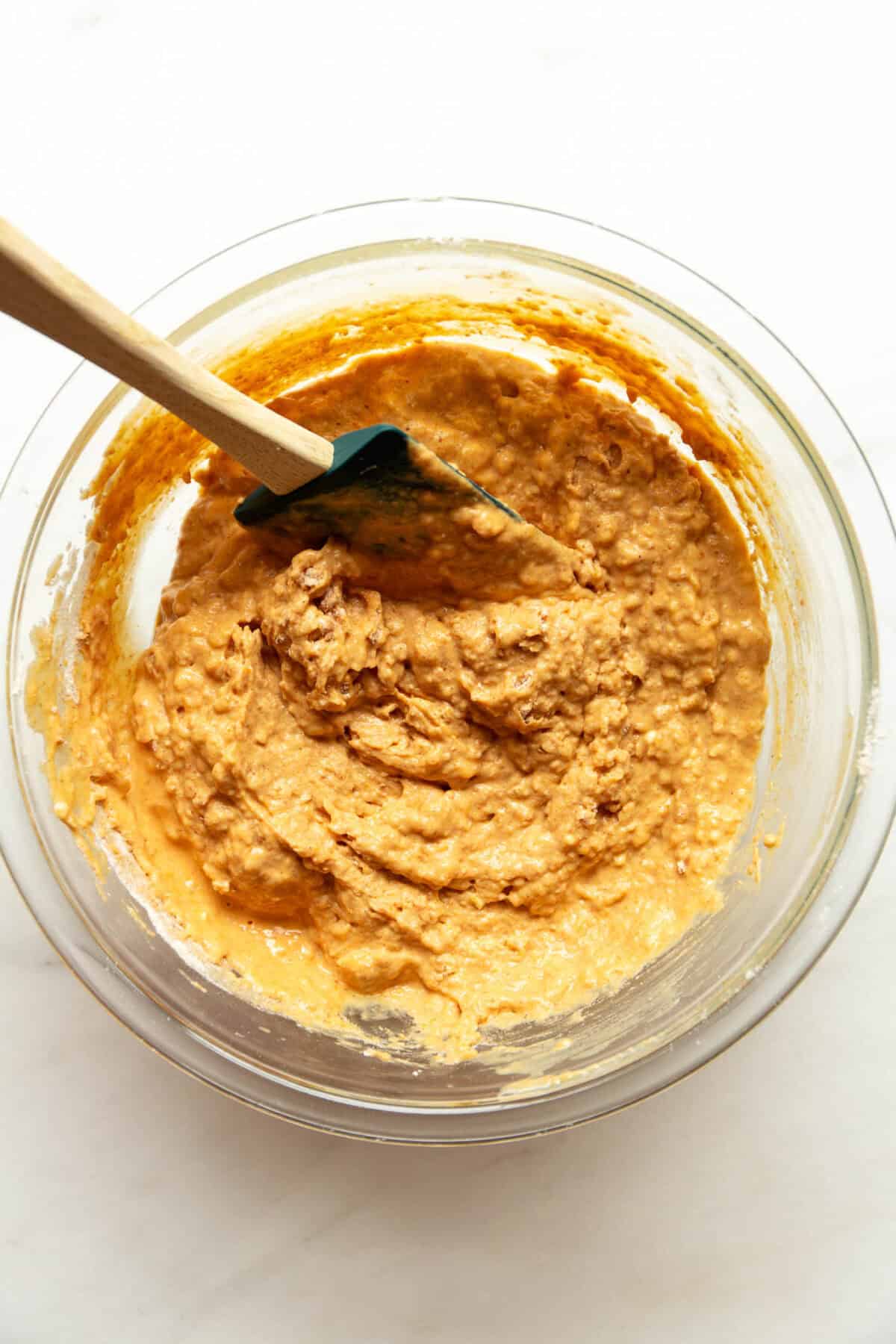 Cottage cheese pumpkin muffin batter stirred together with a rubber spatula in a glass mixing bowl.