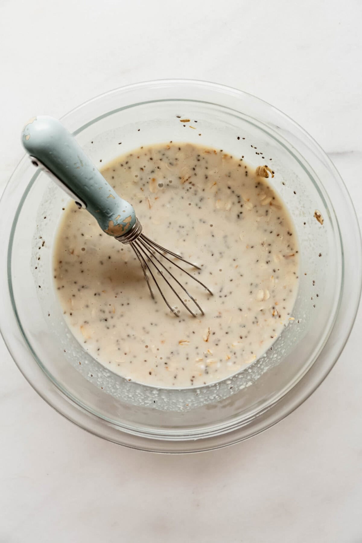 Whisking the overnight oats mixture together in a glass bowl until smooth and combined.