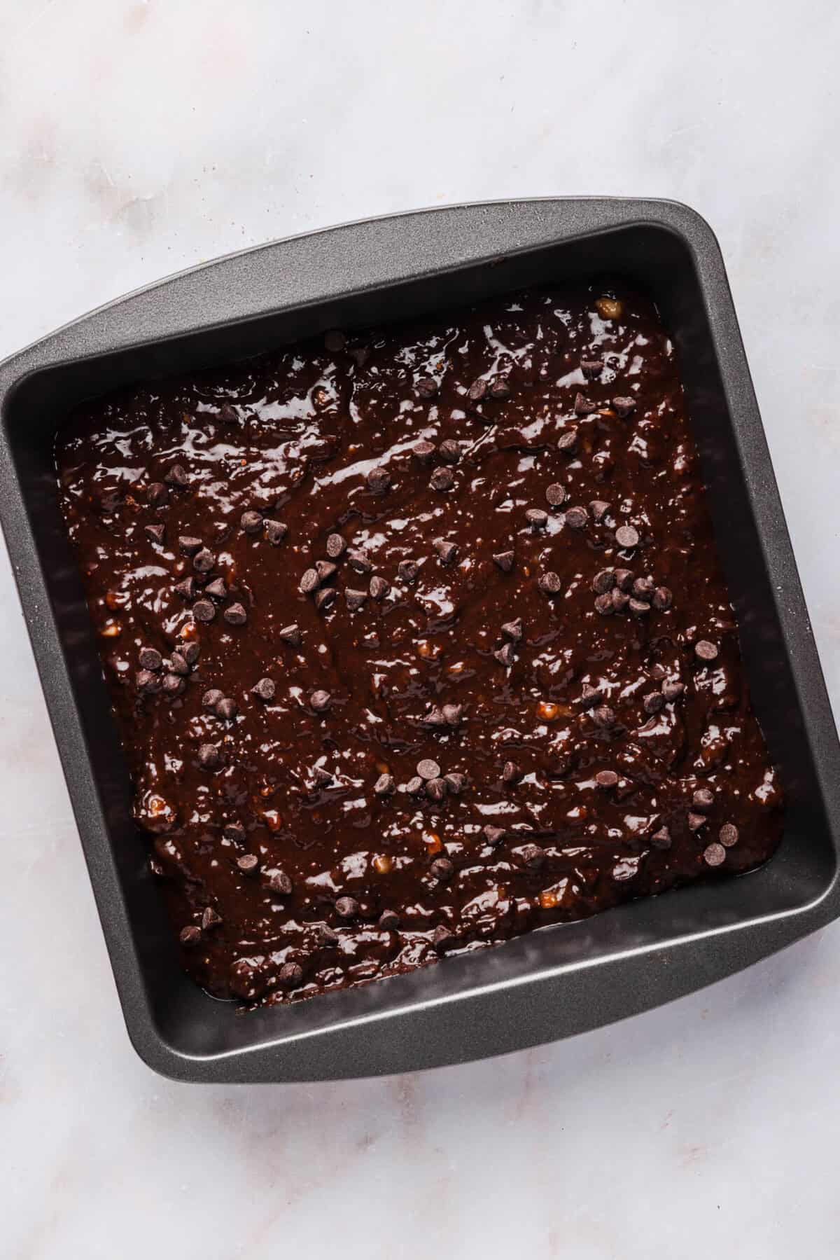 Unbaked banana brownie batter spread evenly in a square baking pan