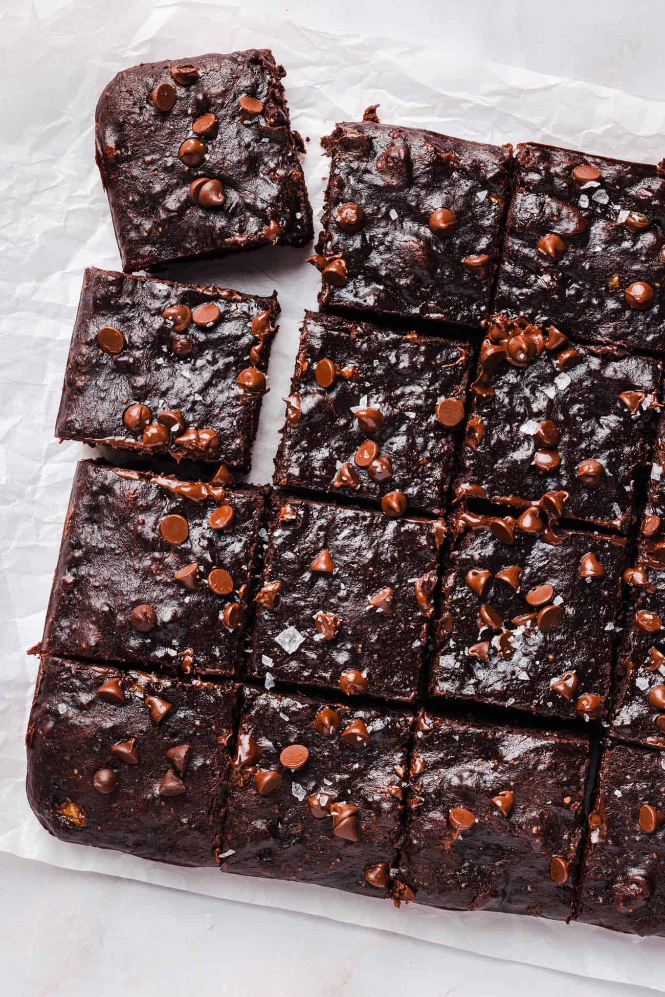 Banana brownies sliced into a grid of squares on parchment paper