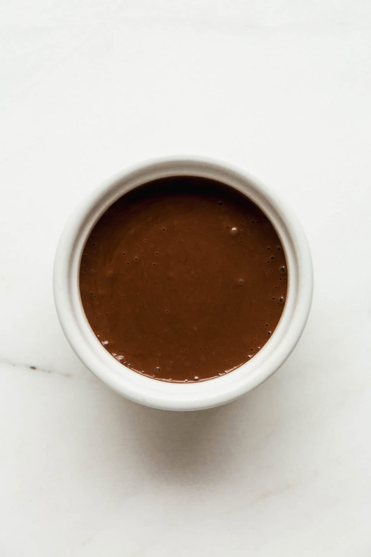 Smooth chocolate batter poured into a white ramekin, ready to bake into a cottage cheese lava cake.