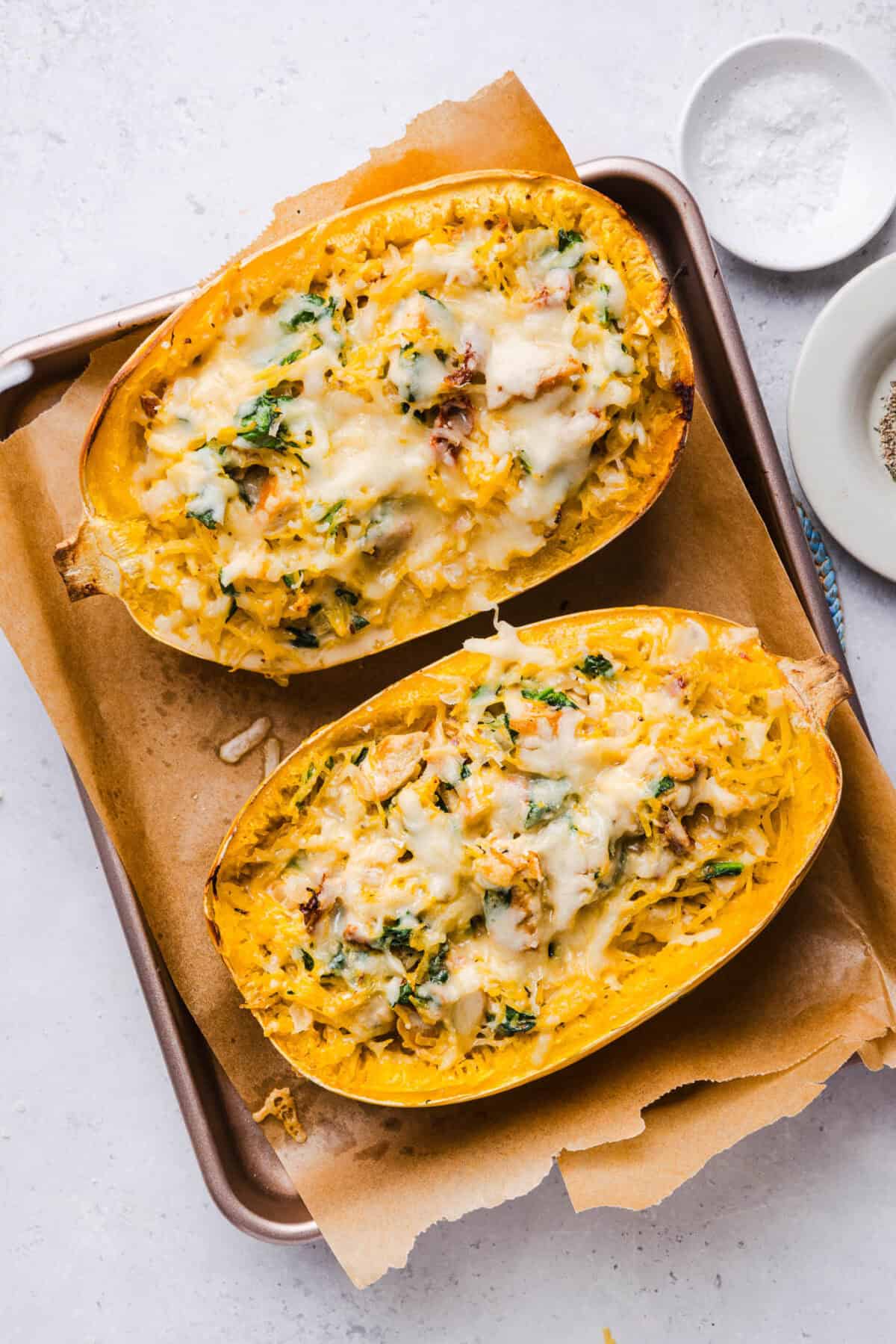 Baked marry me spaghetti squash boats with golden melted cheese on a parchment-lined sheet pan
