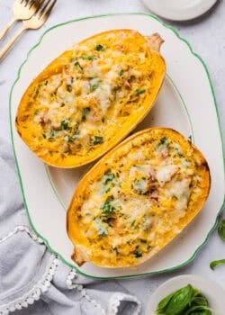 Two halves of marry me spaghetti squash with chicken and spinach served on a white platter