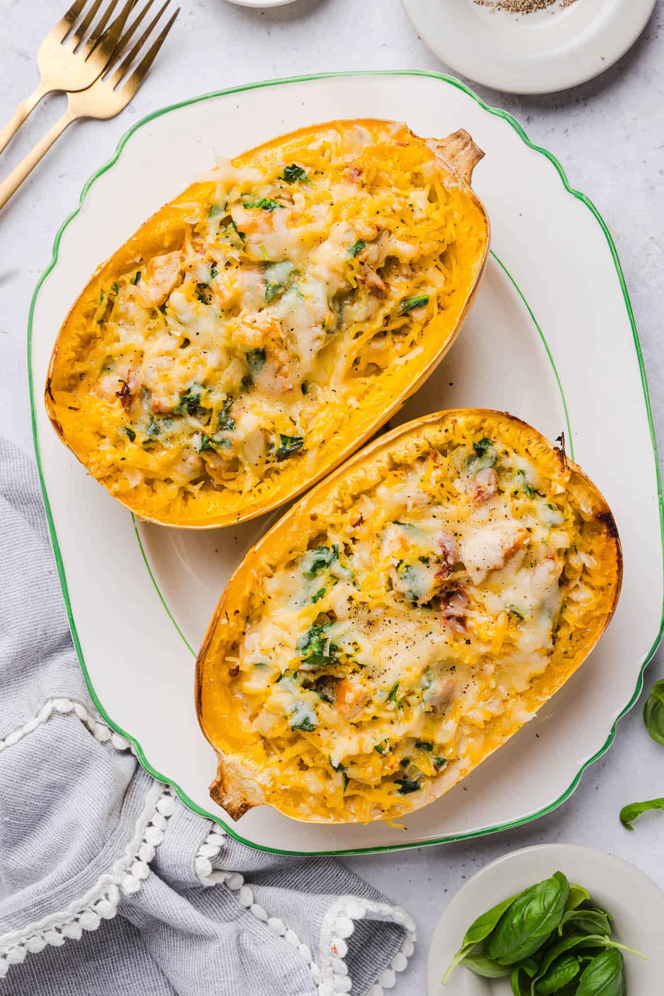 Two halves of marry me spaghetti squash with chicken and spinach served on a white platter