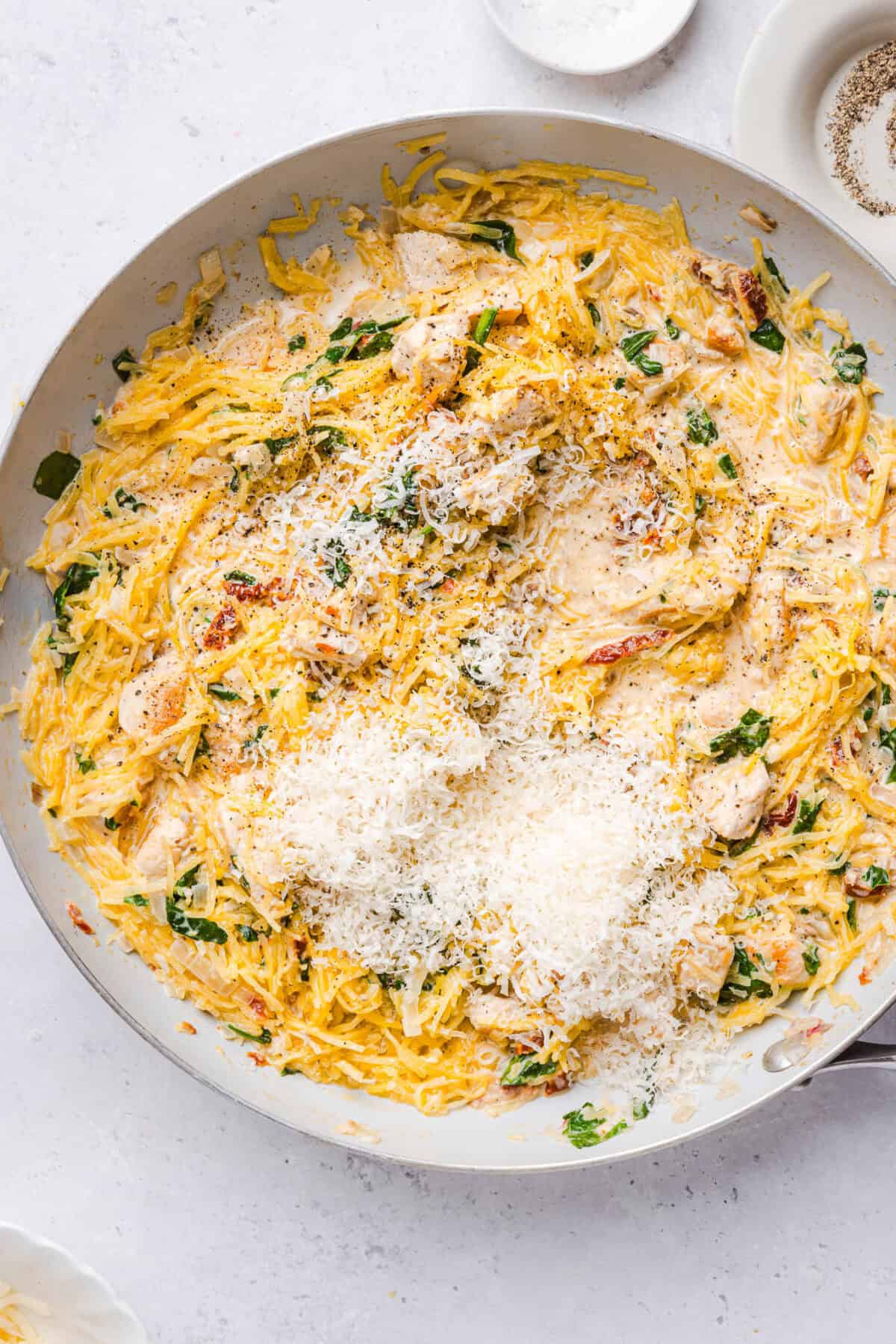 Spaghetti squash strands tossed in creamy marry me sauce with chicken and topped with grated parmesan in a skillet